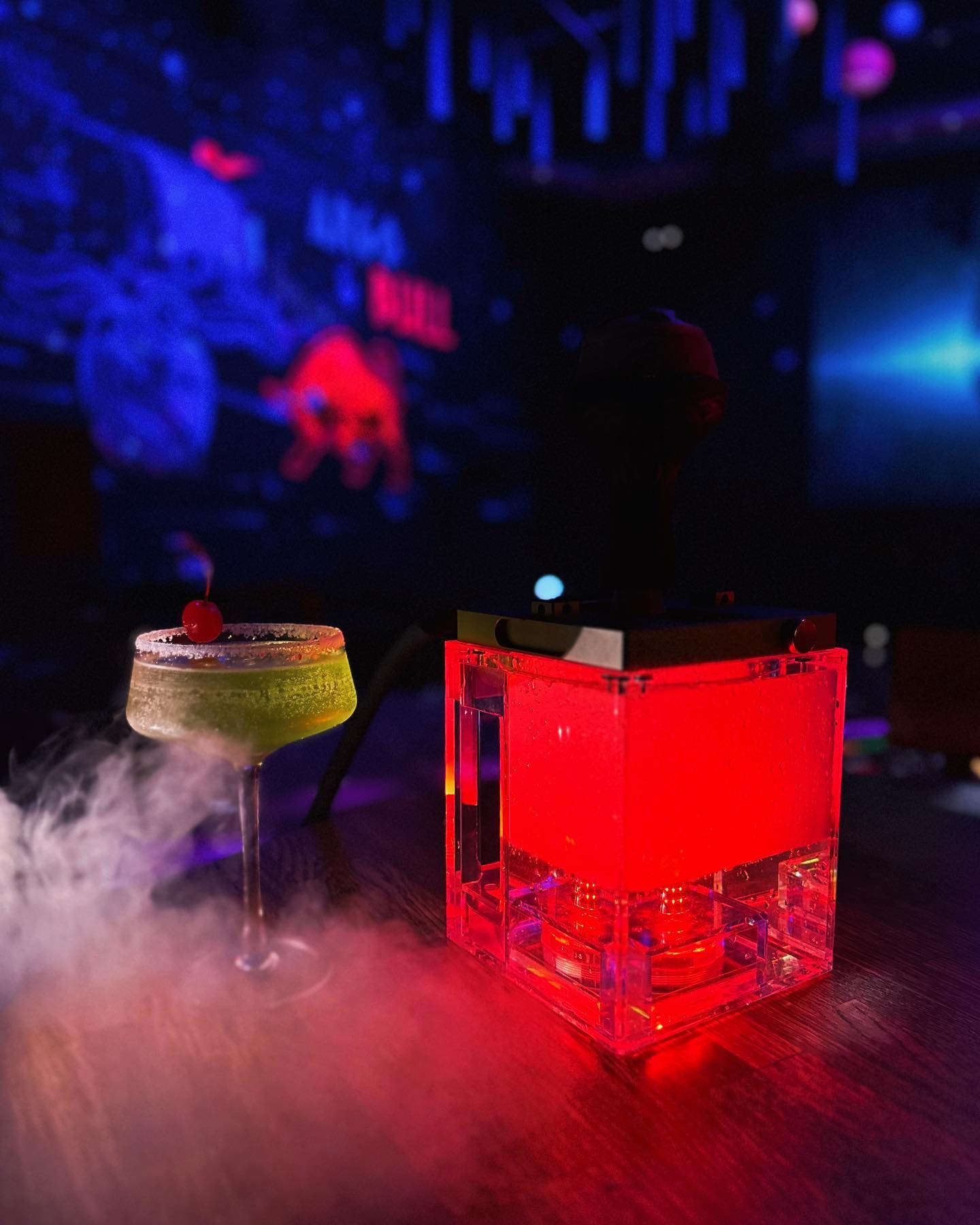 A smoking green cocktail glowing beside a red LED at Argo Lounge