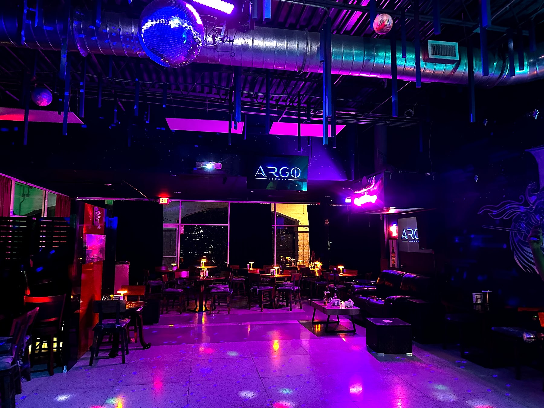 The dance floor under the disco ball with the glowing ARGO sign