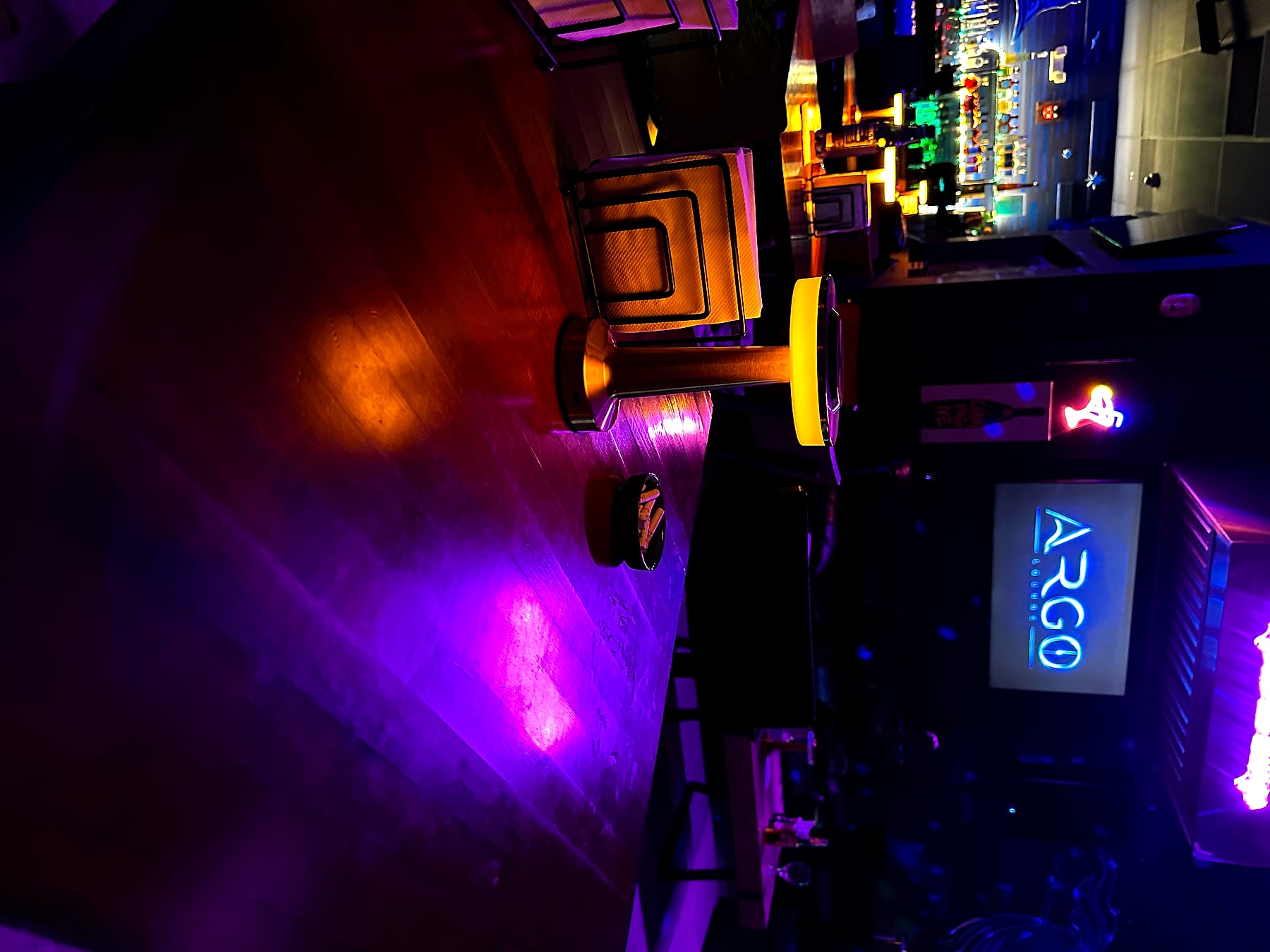 A lounge table with the illuminated Argo Lounge logo behind